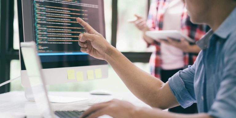 A pair of professionals examining data on a desktop computer, one is examining the computer while one is taking notes, Caber Hill Advisors