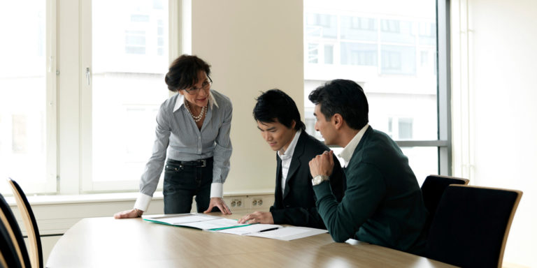 Business meeting between three advisors reviewing a set of documents, Caber Hill Advisors