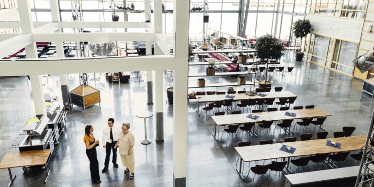 High angle view of colleagues talking in dining hall professional services team in an open office