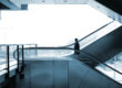 Man on elevator inside an office overlooking a city