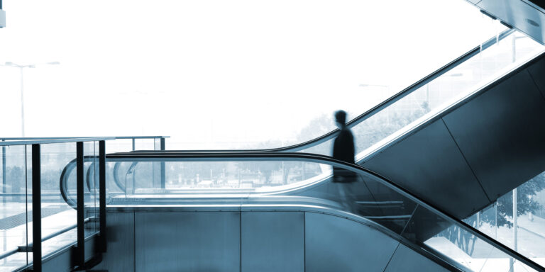 Man on elevator inside an office overlooking a city