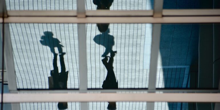 Silhouette of two people outside of a glass office building
